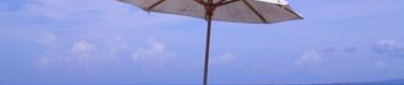Beach chairs under an umbrella on the sand at the beach.