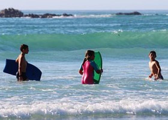 Picture of people at the beach in the water with their boogie boards