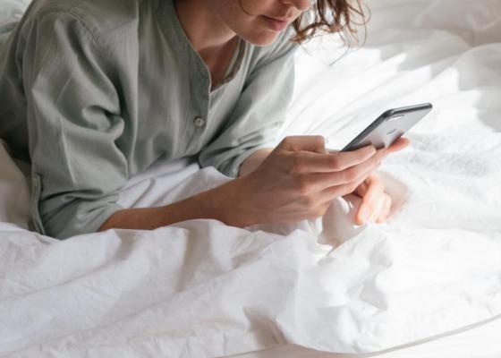 woman using smartphone in bed