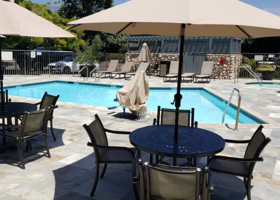 Patio tables and umbrellas poolside, whirlpool in the background